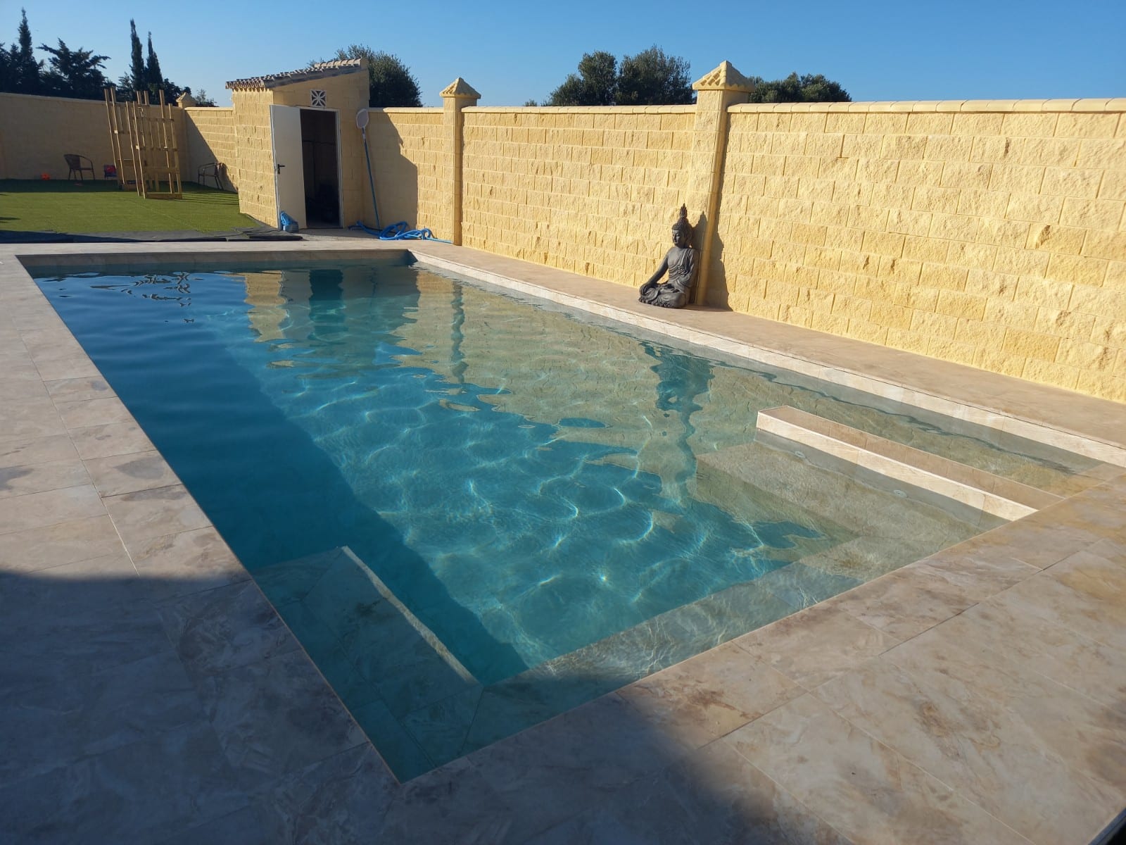 Piscina con agua y pavimento exterior.
