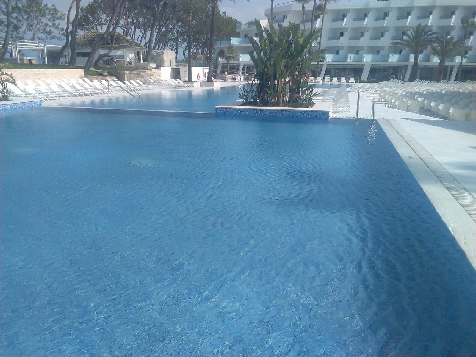 Piscina desbordante con agua al borde y canal de recogida junto al pavimento